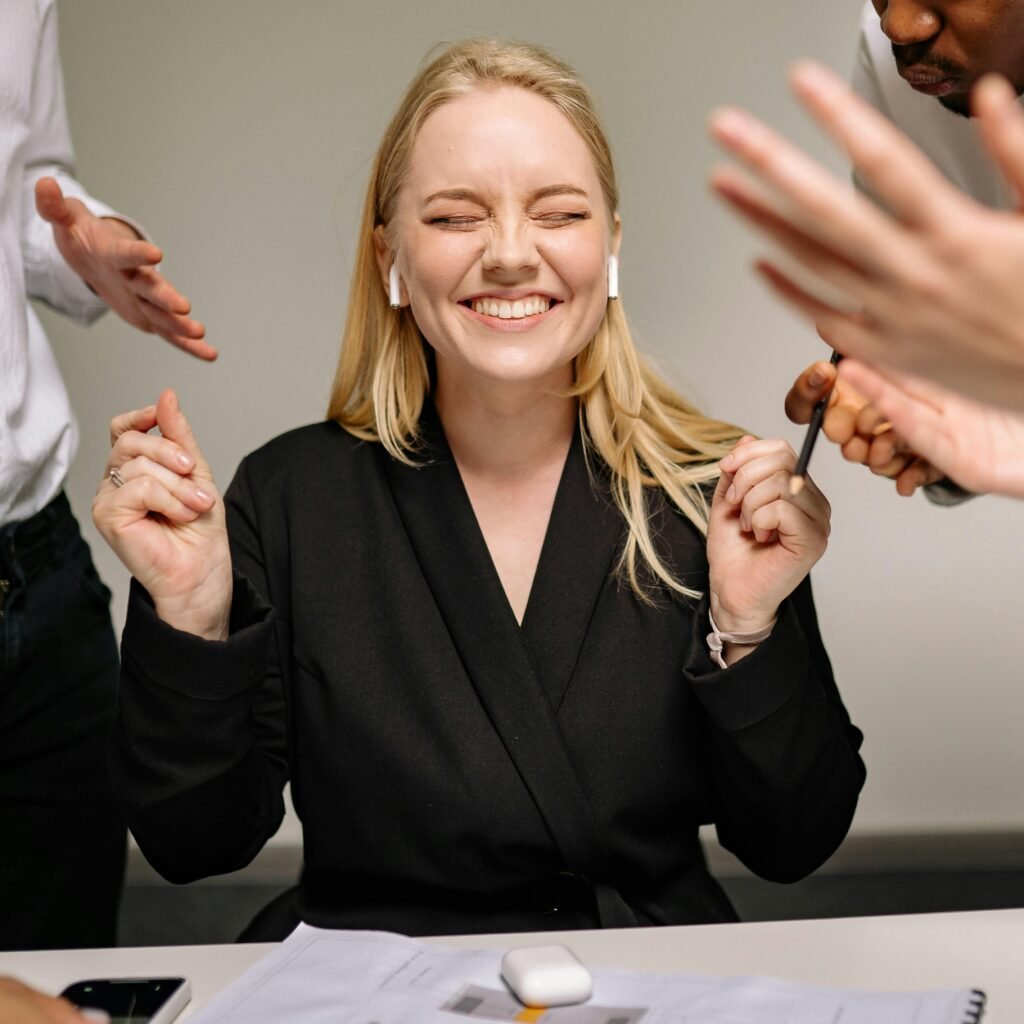 Happy woman smiling with closed eyes and earpods in a business meeting.